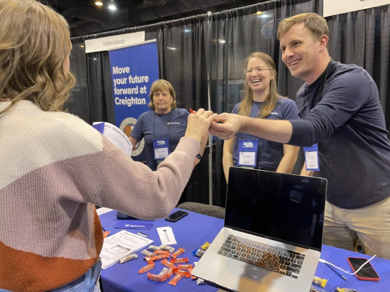 A picture of Short Answer co-founder Adam Sparks handing candy to a teacher at a conference
